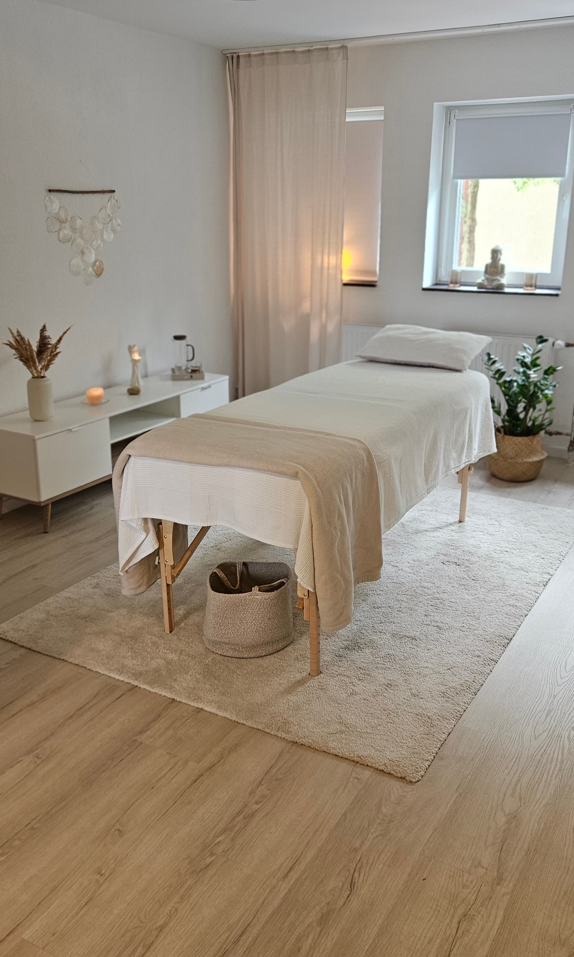 Behandlungsraum mit Massageliege, hellem Holzboden und ruhiger, warmer Einrichtung